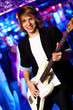 Young guitar player performing in night club