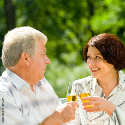 Photo: Senior couple celebrating with champagne, outdoors Senior couple celebrating with champagne, outdoors