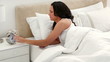 A brunette checks her alarm and goes back to sleep