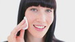 Smiling brunette using a cotton pad