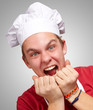 portrait of young cook man screaming over grey background