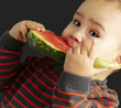 portrait of a handsome kid bitting a watermelon over black backg