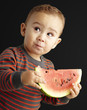 portrait of a handsome kid holding a watermelon and tasting over