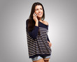 Young woman talking on mobile over grey background