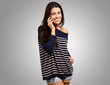 Young woman talking on mobile over grey background