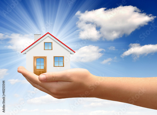 Photo: Little House on the hands against the blue sky Little House on the hands against the blue sky