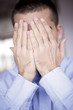 Young man covering face with hands, close-up