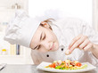 Foto: young chef decorating delicious salad in kitchen young chef decorating delicious salad in kitchen