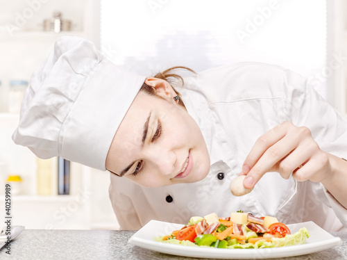 Photo: young chef decorating delicious salad in kitchen young chef decorating delicious salad in kitchen