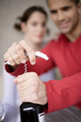 Young man opening wine bottle