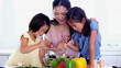 Children helping their mother mix a salad