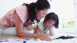 Woman watches a girl as she colours