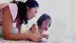Mother and daughter lying together while using a laptop