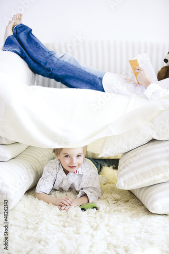 Photo: Boy lying on carpet while father reading book on bed Boy lying on carpet while father reading book on bed