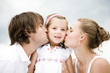 Parents kissing daughter