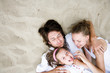 Parents with daughter lying on sand, overhead view