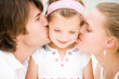 Parents kissing daughter