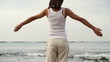 Woman with wide open arms standing on the beach, steadicam shot