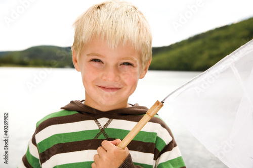 Photo: Boy holding fishing net, smiling, portrait Boy holding fishing net, smiling, portrait