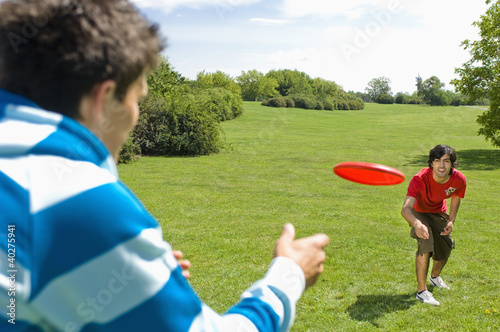 Photo: Friends playing with plastic disc on park Friends playing with plastic disc on park