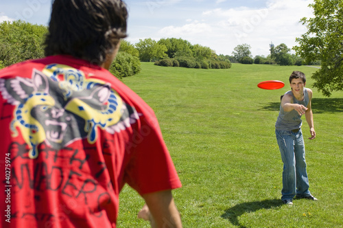 Photo: Friends playing with plastic disc on park Friends playing with plastic disc on park