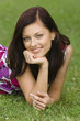 Young woman lying on grass with hand on chin, portrait