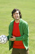 Young man holding soccer ball in park, portrait