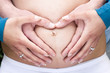 Pregnant Caucasian Woman and Man Making Heart With Hands