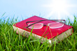Red book on grass with spectacles.