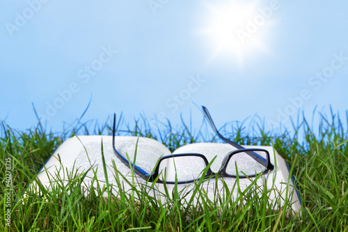 Photo: Open book and spectacles outdoors on a sunny day Open book and spectacles outdoors on a sunny day