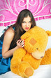 beautiful woman sitting on a bed with teddy bear