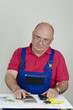 Handwerker mit Bauplan, Taschenrechner und Geld