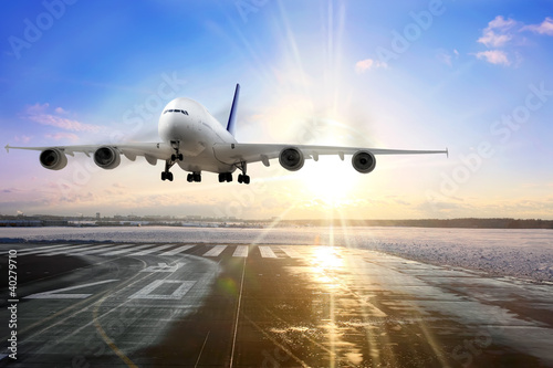 Photo: Passenger airplane landing on runway in airport. Evening Passenger airplane landing on runway in airport. Evening