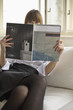 Young woman holding magazine while sitting on sofa