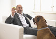 Businessman sitting on sofa, playing with dog
