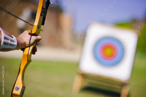 Foto: Archer who holds his bow aims at target Archer who holds his bow aims at target