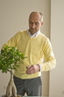 Mature man pruning potted plant with scissors