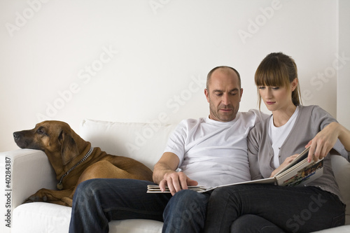 Photo: Couple sitting on sofa, looking at catalog Couple sitting on sofa, looking at catalog