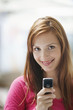 Young woman holding mobile phone, smiling, portrait