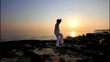 Man practicing Tai Chi at sunrise on the beach