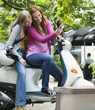 Young women sitting on motor scooter while young men smiling