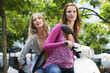 Young women sitting on motor scooter, smiling
