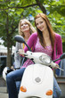 Young women sitting on motor scooter, smiling, portrait