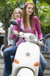 Young women sitting on motor scooter, smiling, portrait