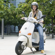 Young woman sitting on motor scooter, portrait