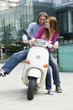 Young couples sitting on motor scooter, smiling
