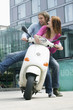Young couples sitting on motor scooter, smiling
