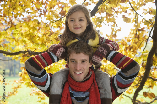 Photo: Father carrying daughter on shoulders, smiling Father carrying daughter on shoulders, smiling