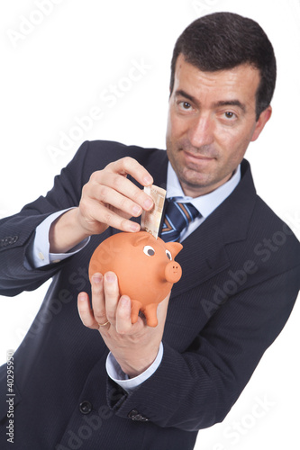Photo: man holding a piggy bang and putting bills inside man holding a piggy bang and putting bills inside