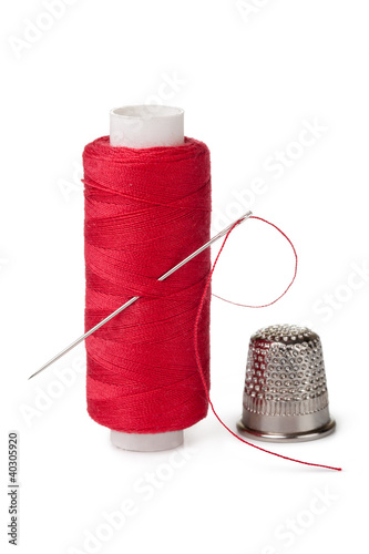 Photo: red bobbins of thread and needle isolated on white background red bobbins of thread and needle isolated on white background